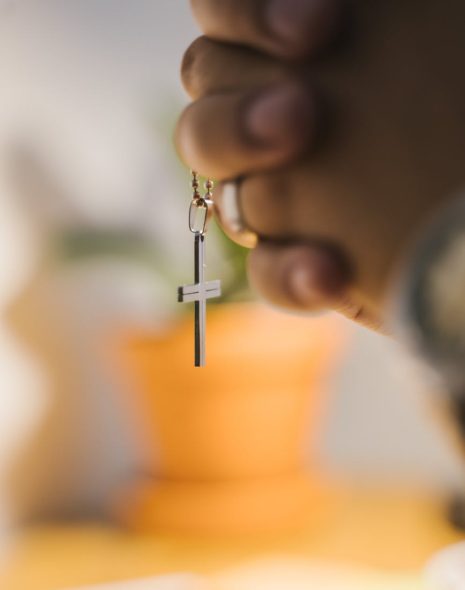 close up shot of a person holding a cross pendant